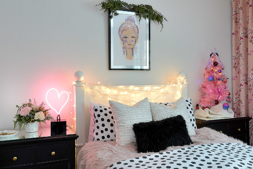 Pink Christmas bedroom: Fun and cozy bedroom with a pink Christmas tree, polka-dot bedding, fairy lights, and a neon heart light.