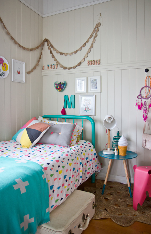 Aménagement d'une chambre d'enfant éclectique avec un mur beige et un sol en bois brun.