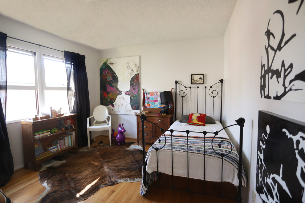 Exempel på ett eklektiskt könsneutralt barnrum kombinerat med sovrum och för 4-10-åringar, med vita väggar och mellanmörkt trägolv