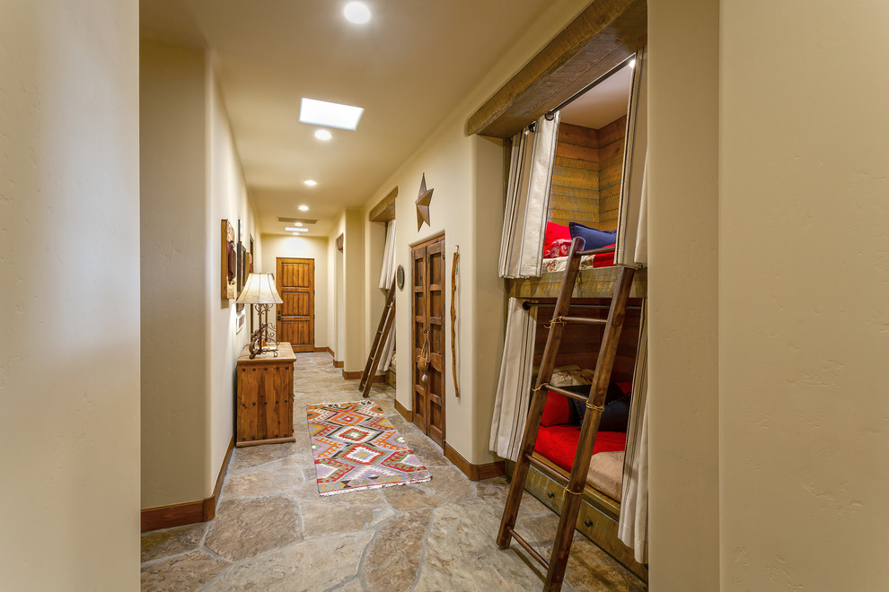 Exempel på ett stort amerikanskt könsneutralt barnrum kombinerat med sovrum och för 4-10-åringar, med beige väggar, skiffergolv och flerfärgat golv