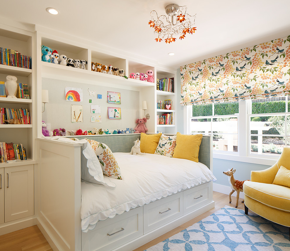 Photo of a small classic children’s room for girls in San Francisco with blue walls, light hardwood flooring and brown floors.