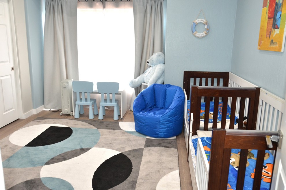 На фото: детская среднего размера в современном стиле с спальным местом, синими стенами, паркетным полом среднего тона и бежевым полом для ребенка от 1 до 3 лет, мальчика