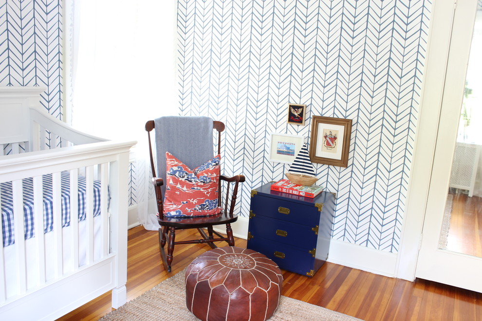 This is an example of a beach style nursery in New York with blue walls and medium hardwood flooring.