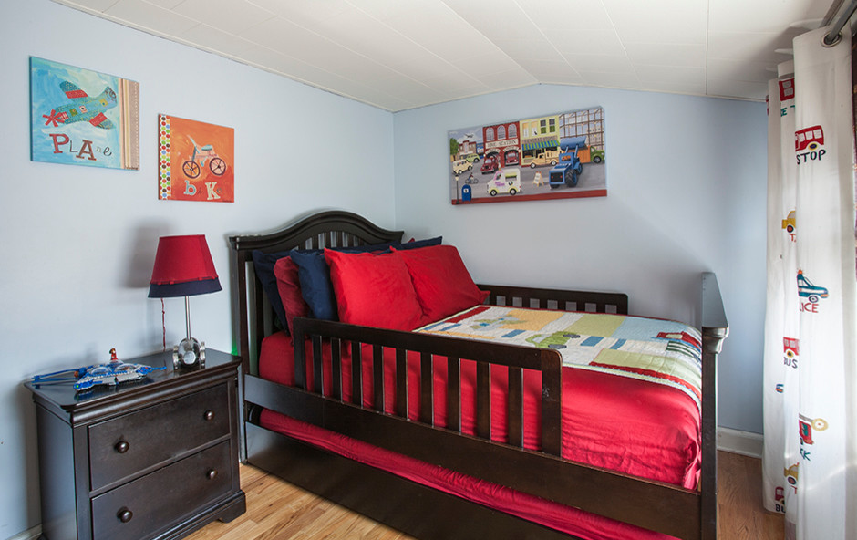 This is an example of a medium sized traditional children’s room for boys in New York with blue walls and light hardwood flooring.