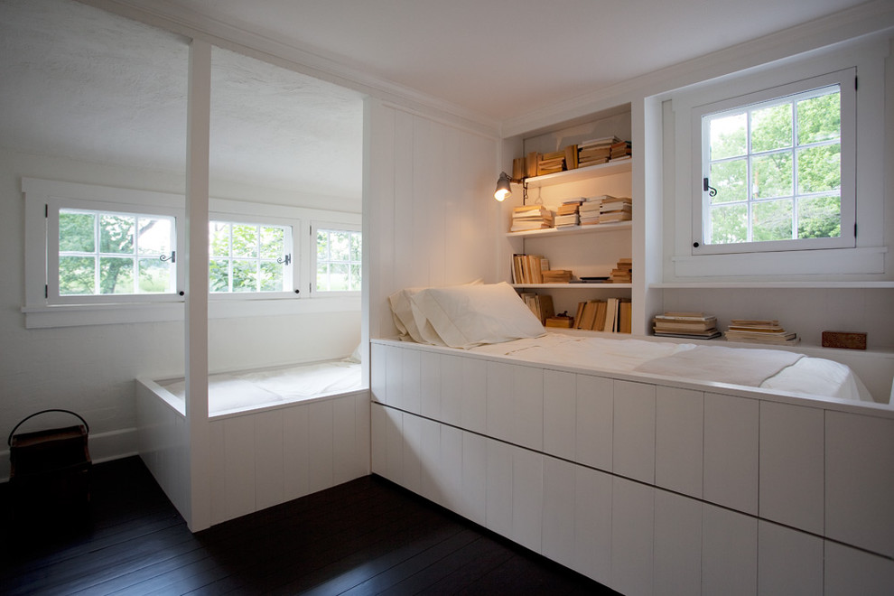 Foto på ett lantligt könsneutralt barnrum kombinerat med sovrum, med vita väggar och mörkt trägolv