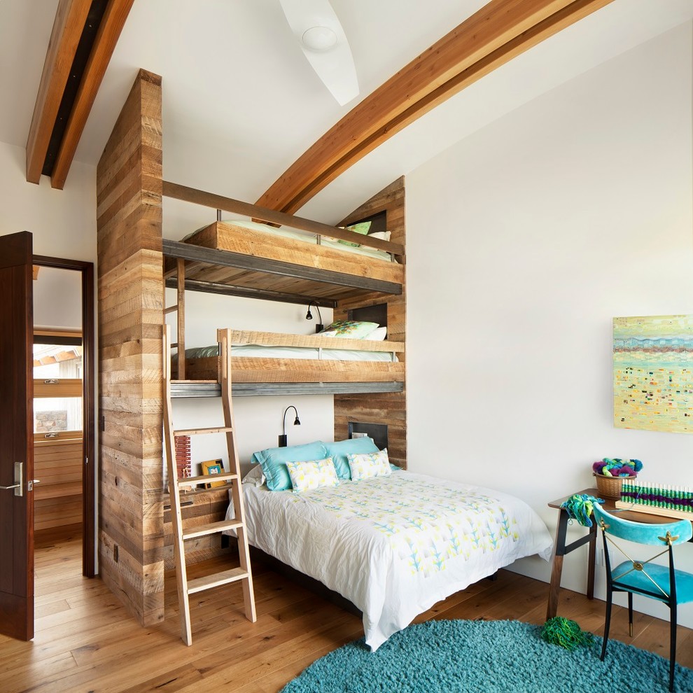 Bild på ett rustikt könsneutralt barnrum kombinerat med sovrum, med vita väggar och mellanmörkt trägolv