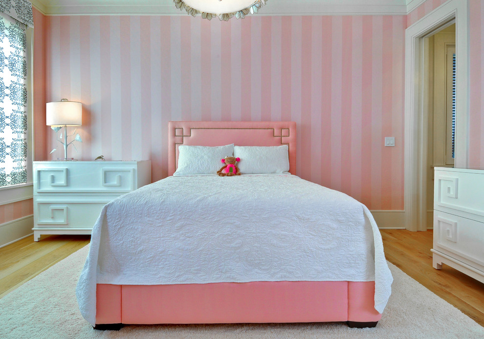 Inredning av ett klassiskt flickrum kombinerat med sovrum och för 4-10-åringar, med rosa väggar och mellanmörkt trägolv