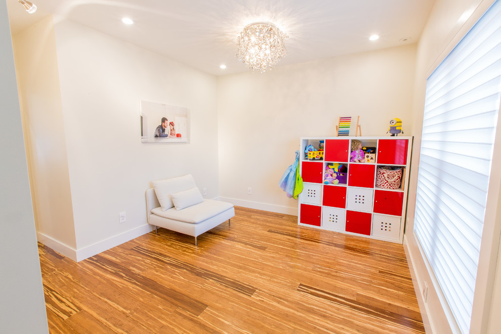 Idée de décoration pour une chambre d'enfant de 1 à 3 ans design de taille moyenne avec un mur blanc, parquet en bambou et un sol marron.