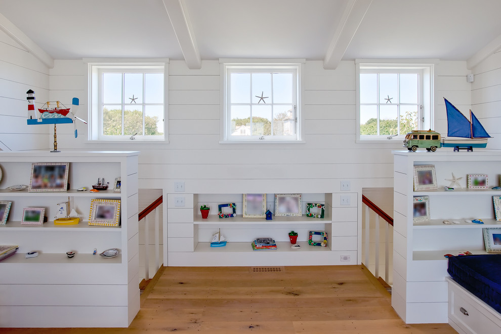 Large beach style gender-neutral medium tone wood floor kids' room photo in Boston with white walls