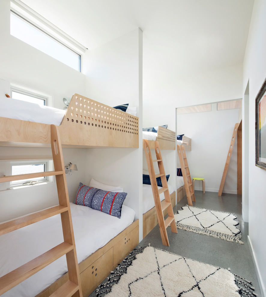 Cette image montre une petite chambre d'enfant marine avec un mur blanc, un sol gris et un lit superposé.