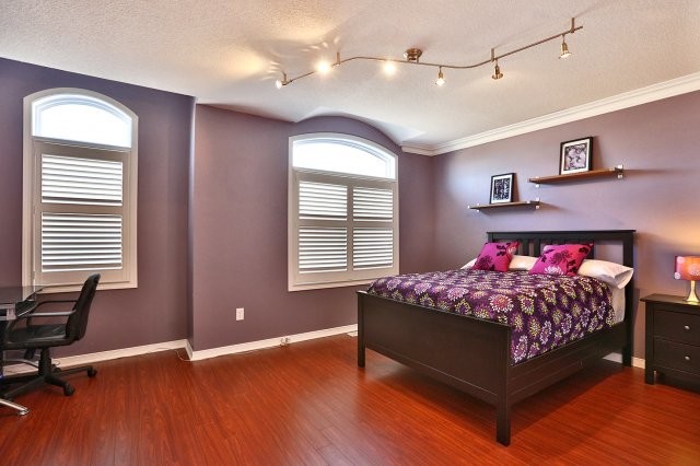 Idée de décoration pour une grande chambre d'enfant minimaliste avec un mur violet et un sol en bois brun.