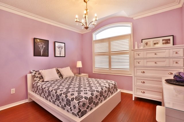 Modern inredning av ett barnrum kombinerat med sovrum, med lila väggar och mellanmörkt trägolv