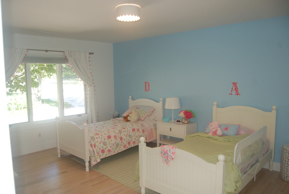 Ispirazione per una cameretta per bambini da 4 a 10 anni design di medie dimensioni con pareti bianche e pavimento in legno massello medio