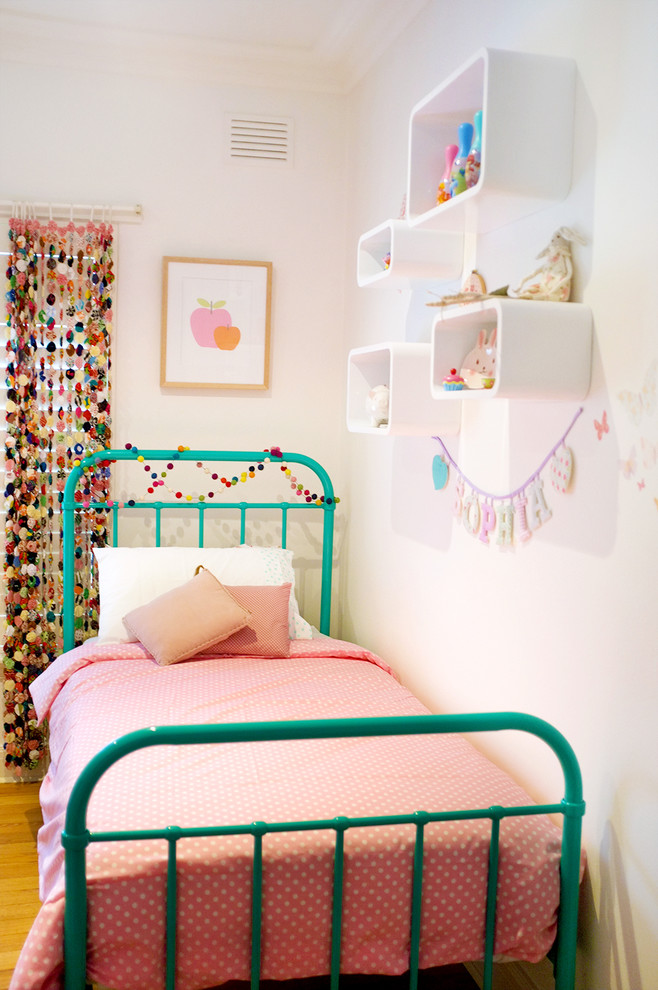 Imagen de dormitorio infantil de 4 a 10 años actual de tamaño medio con paredes blancas y suelo de madera en tonos medios