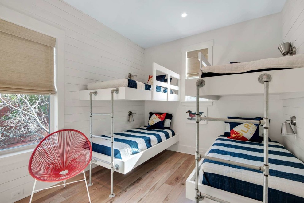 Foto på ett mellanstort maritimt könsneutralt barnrum kombinerat med sovrum och för 4-10-åringar, med vita väggar, ljust trägolv och brunt golv