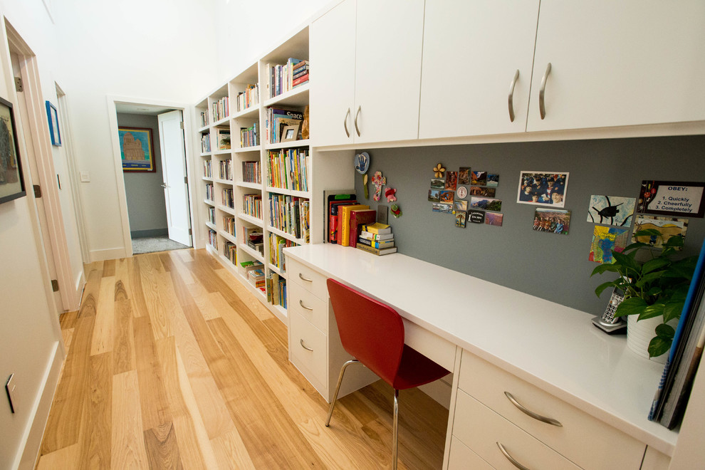 Idéer för stora funkis könsneutrala tonårsrum kombinerat med skrivbord, med vita väggar, mellanmörkt trägolv och brunt golv