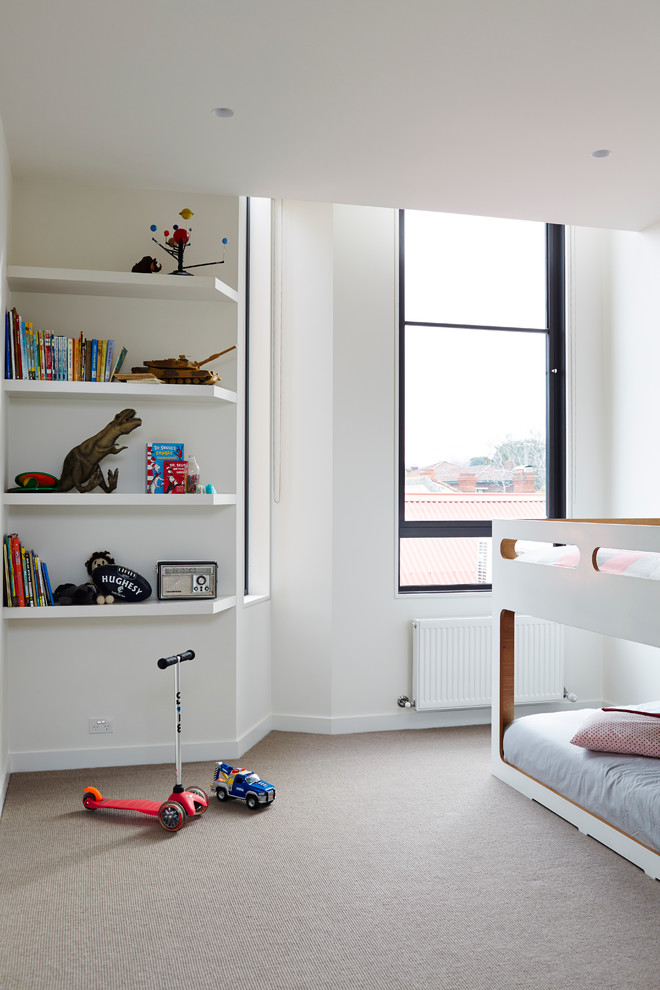 На фото: нейтральная детская в современном стиле с спальным местом, белыми стенами и ковровым покрытием для ребенка от 4 до 10 лет с