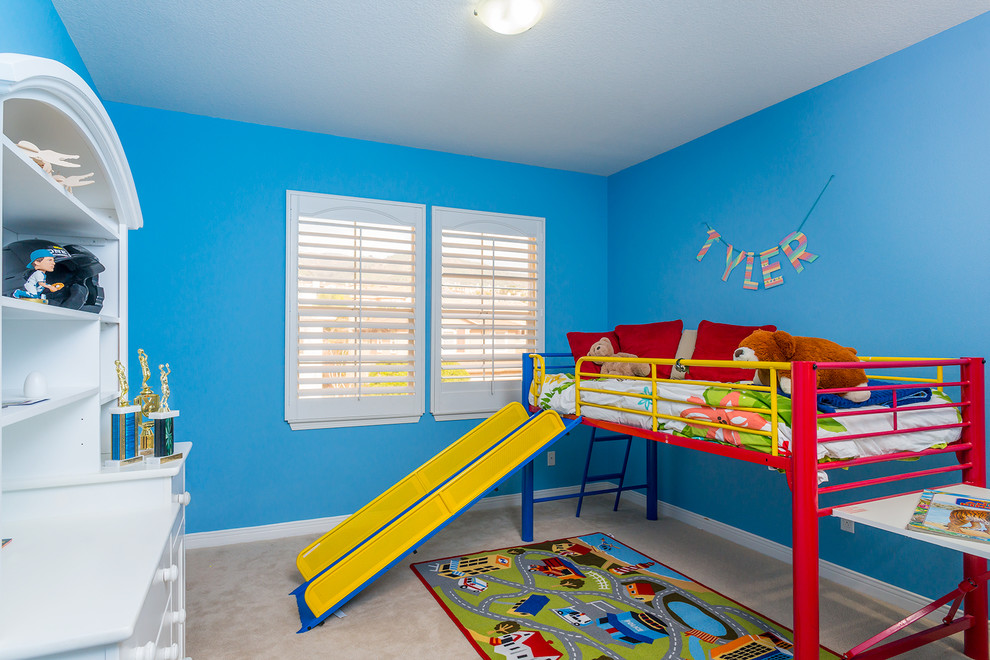 Medium sized bohemian children’s room for boys in Los Angeles with blue walls and carpet.