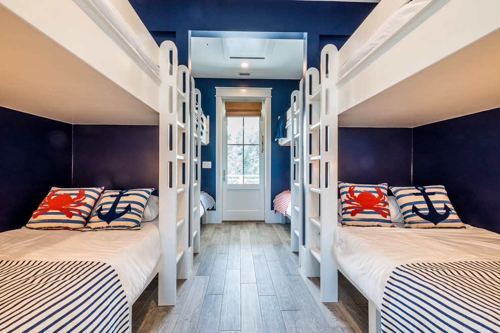 Idéer för maritima könsneutrala barnrum kombinerat med sovrum och för 4-10-åringar, med blå väggar och mellanmörkt trägolv