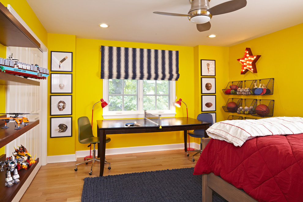 Inredning av ett modernt mellanstort pojkrum kombinerat med sovrum och för 4-10-åringar, med gula väggar och mellanmörkt trägolv
