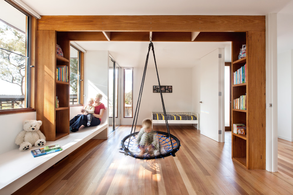 Cette image montre une grande chambre d'enfant design avec un sol en bois brun et un mur blanc.