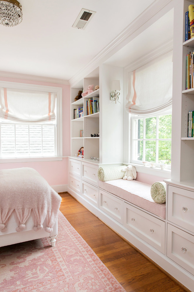 Klassisk inredning av ett flickrum kombinerat med sovrum, med rosa väggar, mellanmörkt trägolv och beiget golv