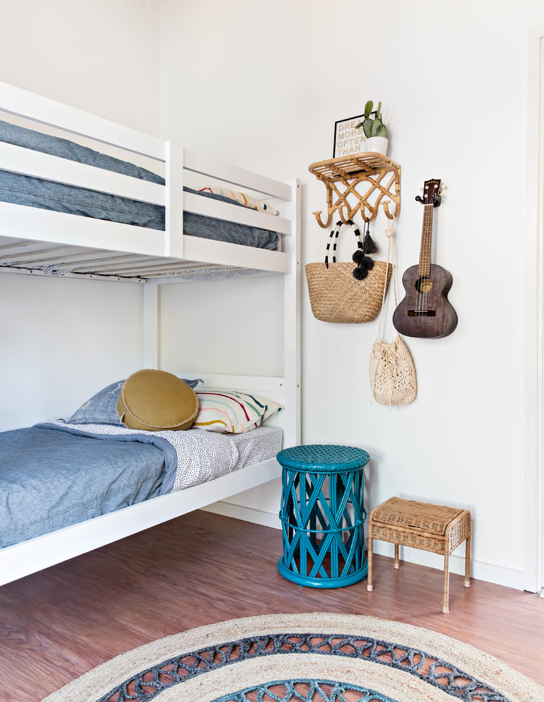 Ejemplo de dormitorio infantil costero con paredes blancas, suelo de madera en tonos medios y suelo marrón
