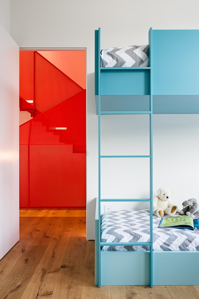 Réalisation d'une petite chambre d'enfant de 4 à 10 ans design avec un mur blanc, un sol marron, un sol en bois brun et un lit superposé.