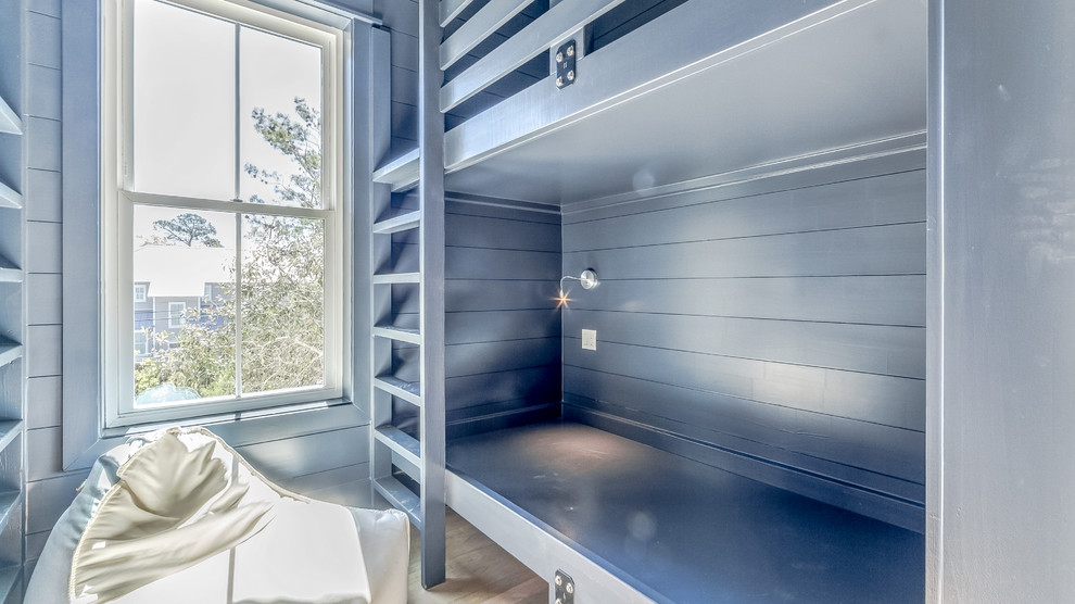 Immagine di una cameretta per bambini da 4 a 10 anni stile marino di medie dimensioni con pareti blu, pavimento in legno massello medio e pavimento marrone