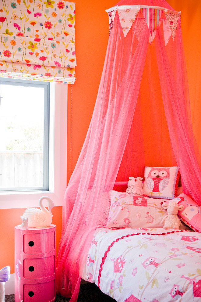 Foto på ett barnrum kombinerat med sovrum, med orange väggar