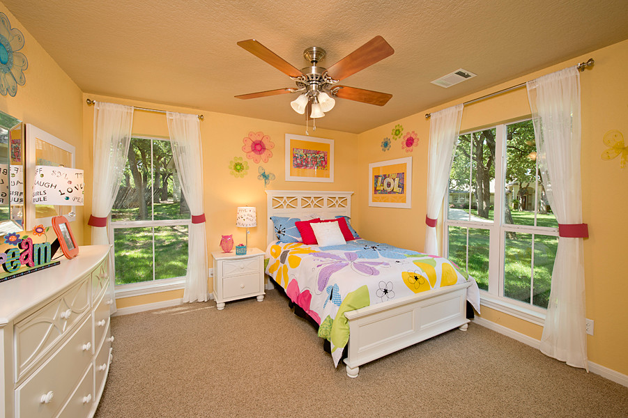 Medium sized classic children’s room for girls in Houston with yellow walls, carpet and brown floors.
