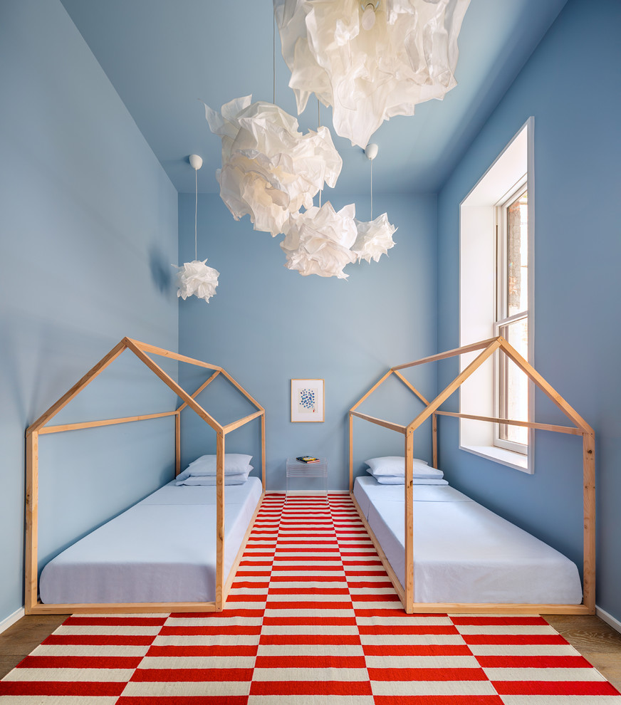 Cette image montre une grande chambre d'enfant de 4 à 10 ans design avec un mur bleu, parquet clair et un sol marron.
