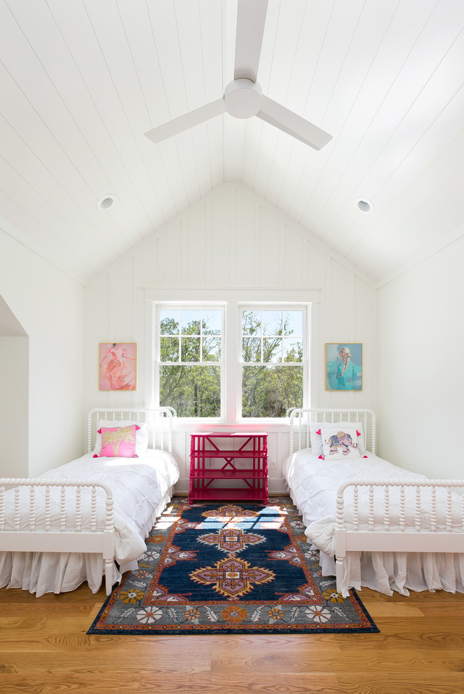 This is an example of a medium sized rural children’s room for girls in Charleston with white walls, medium hardwood flooring and brown floors.