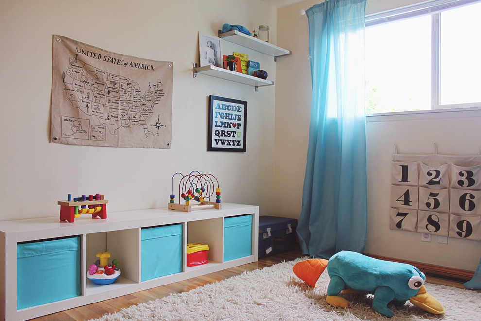 Medium sized modern toddler’s room for boys in Seattle with white walls and light hardwood flooring.