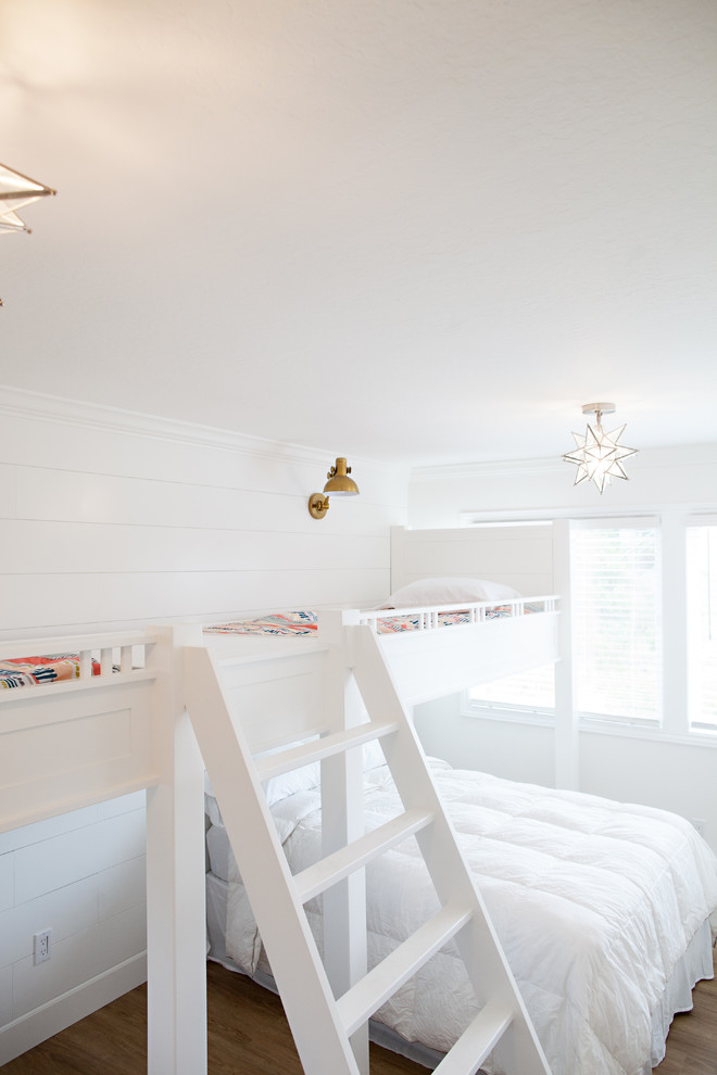 Modelo de dormitorio infantil de 4 a 10 años costero grande con paredes blancas y suelo de madera en tonos medios