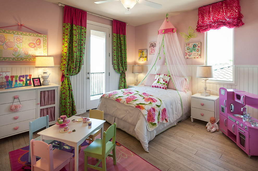 Imagen de dormitorio infantil de 4 a 10 años clásico con paredes rosas y suelo de madera en tonos medios