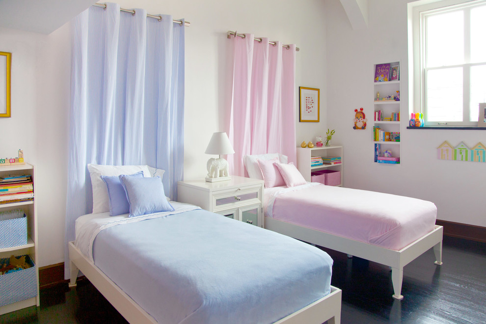 This is an example of a medium sized classic gender neutral toddler’s room in New York with white walls and dark hardwood flooring.