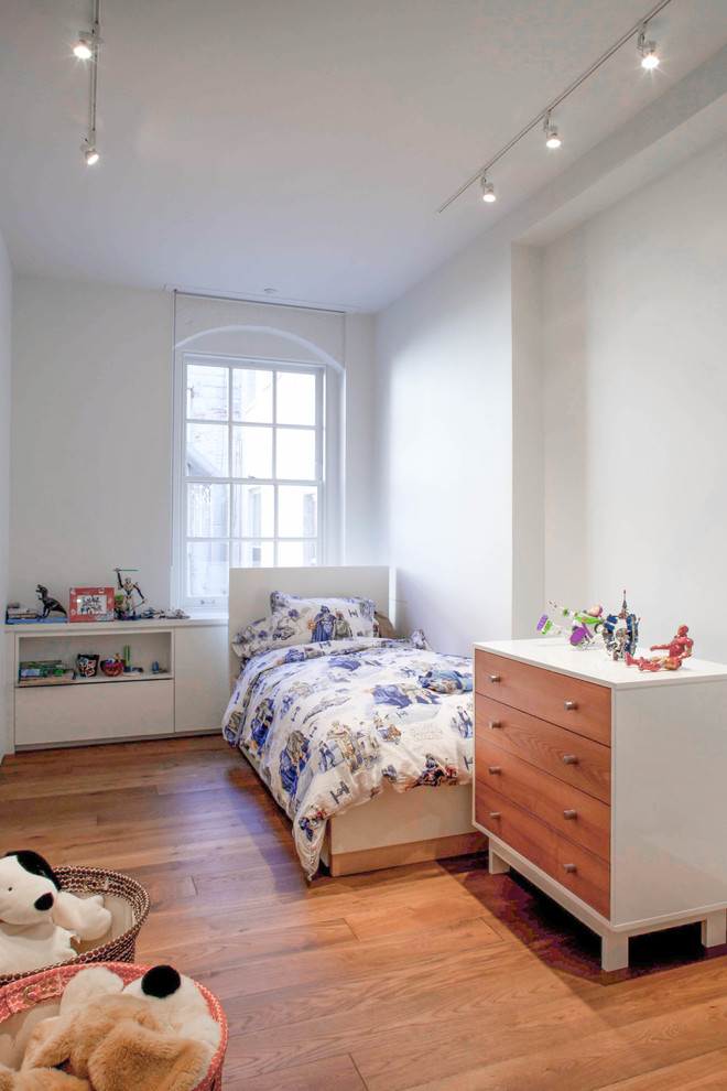 Immagine di una cameretta per bambini da 1 a 3 anni minimal con pareti bianche e pavimento in legno massello medio