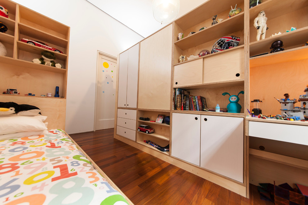 Foto på ett mellanstort funkis könsneutralt barnrum kombinerat med sovrum och för 4-10-åringar, med vita väggar och mellanmörkt trägolv