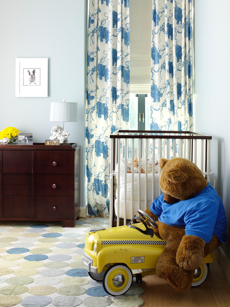 Medium sized contemporary gender neutral toddler’s room in New York with blue walls and light hardwood flooring.