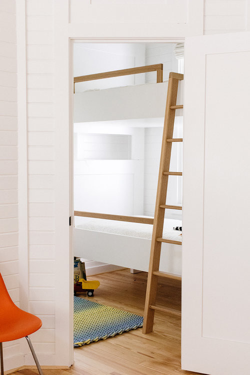 Immagine di una piccola cameretta per bambini da 4 a 10 anni stile marinaro con pareti bianche, parquet chiaro e pavimento marrone