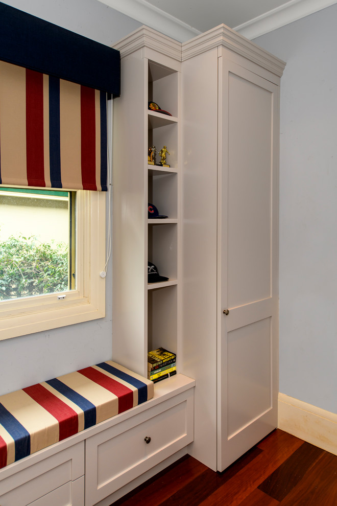 Inspiration för små klassiska barnrum kombinerat med sovrum, med blå väggar, mörkt trägolv och brunt golv