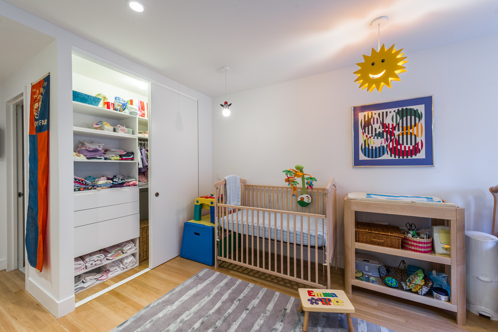 Modelo de dormitorio infantil actual grande con paredes blancas y suelo de madera clara