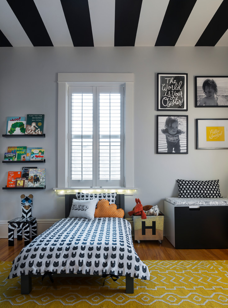 Photo of a small traditional toddler’s room for boys in Chicago with grey walls, medium hardwood flooring and brown floors.