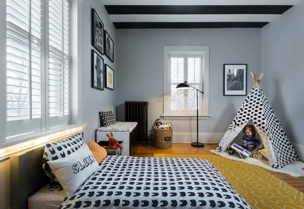 This is an example of a small contemporary toddler’s room for boys in Chicago with grey walls and light hardwood flooring.