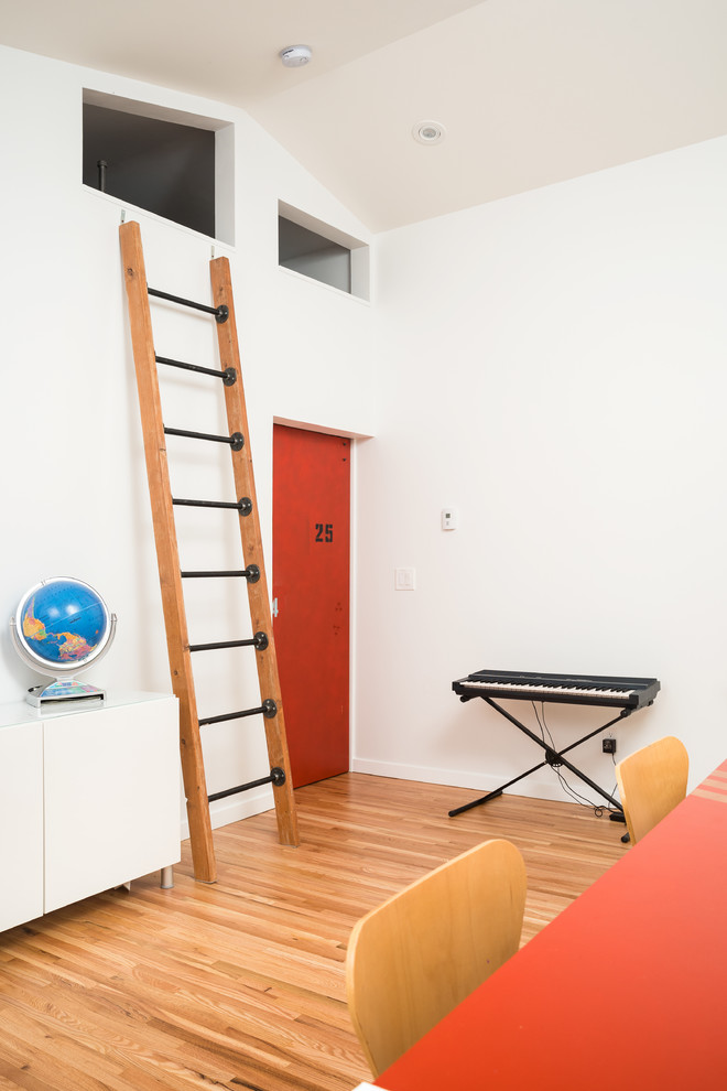 Esempio di una cameretta per bambini contemporanea di medie dimensioni con pareti bianche, parquet chiaro e pavimento marrone
