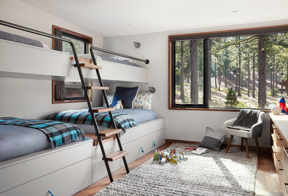 Diseño de dormitorio infantil actual grande con paredes blancas, suelo marrón y suelo de madera en tonos medios