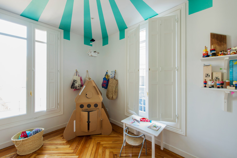 Cette photo montre une chambre neutre de 4 à 10 ans tendance de taille moyenne avec un bureau, un mur blanc et un sol en bois brun.
