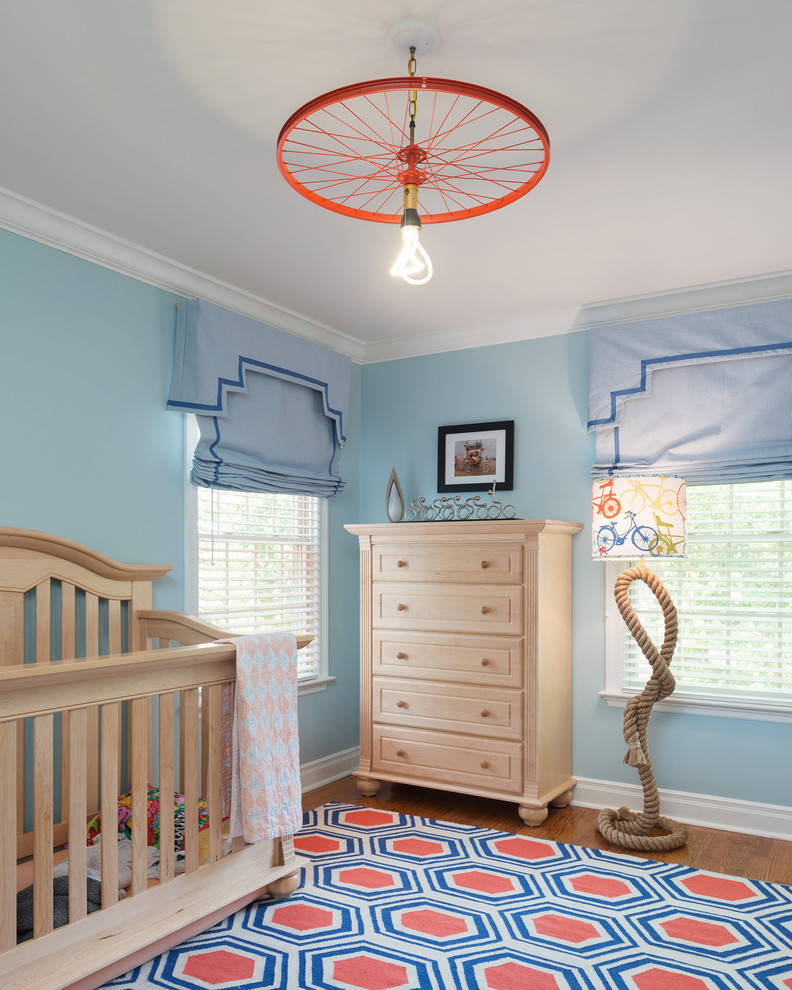 Idée de décoration pour une chambre d'enfant de 1 à 3 ans tradition de taille moyenne avec un mur bleu et un sol en bois brun.
