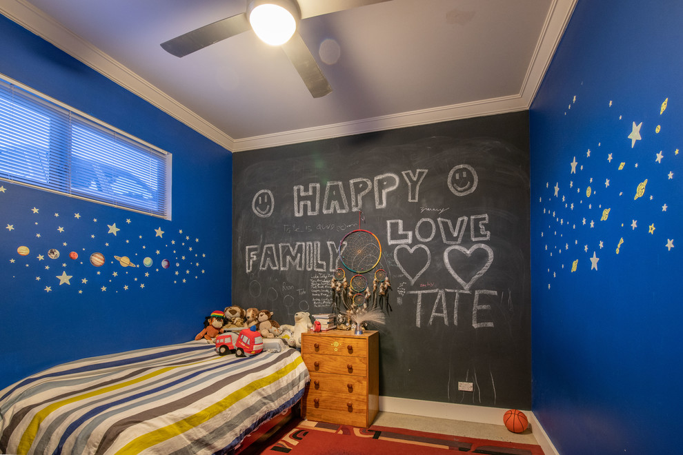 Modelo de dormitorio infantil actual de tamaño medio con paredes azules, suelo de cemento y suelo beige